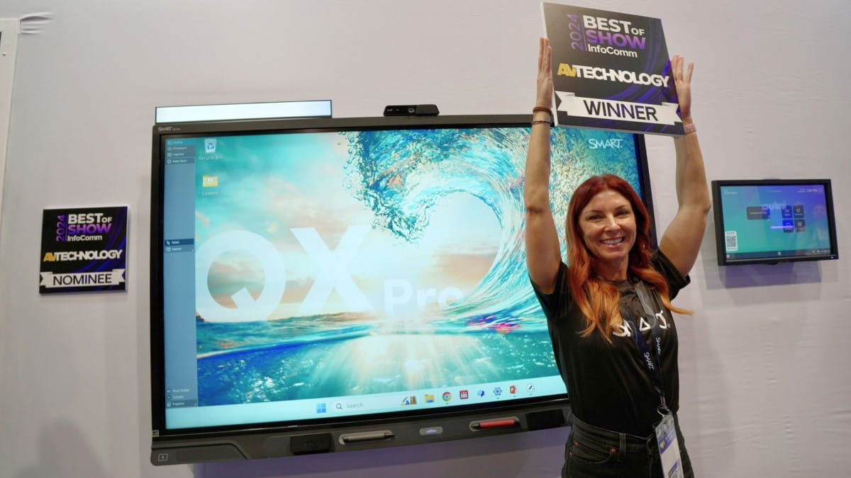 SMART representative, Jessica Secan, holding up the ‘Winner” sign in front of the SMART Board QX Pro at InfoComm.