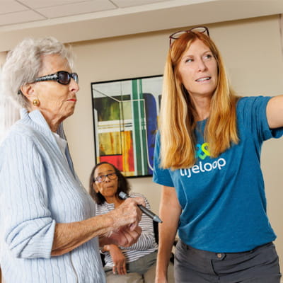 A senior and caregiver interacting with digital content on a SMART Board.