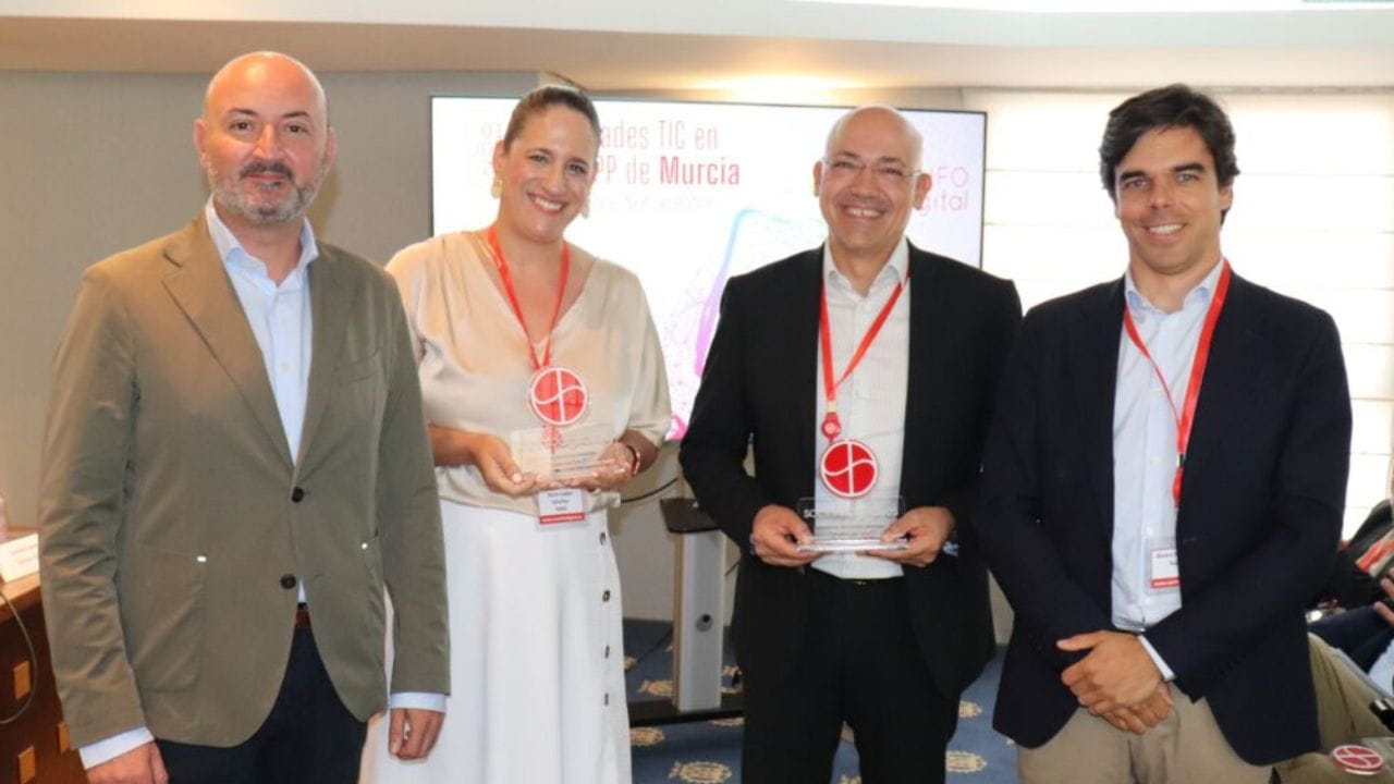 Group photo of four professionals at a conference, two of whom are holding awards.