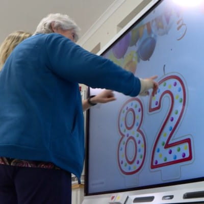 A senior from Port Macquarie elderly care facility taking part in an interactive activity on a SMART Board.