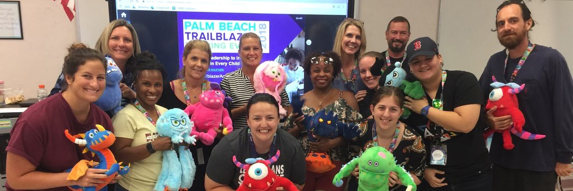 A group of happy teachers with SMART monster stuffed animals.