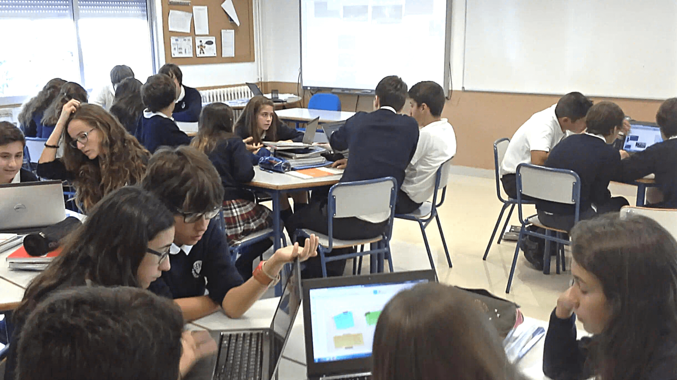 Students at the SEK International School Atlantico working collaboratively in small, breakout groups with student devices.